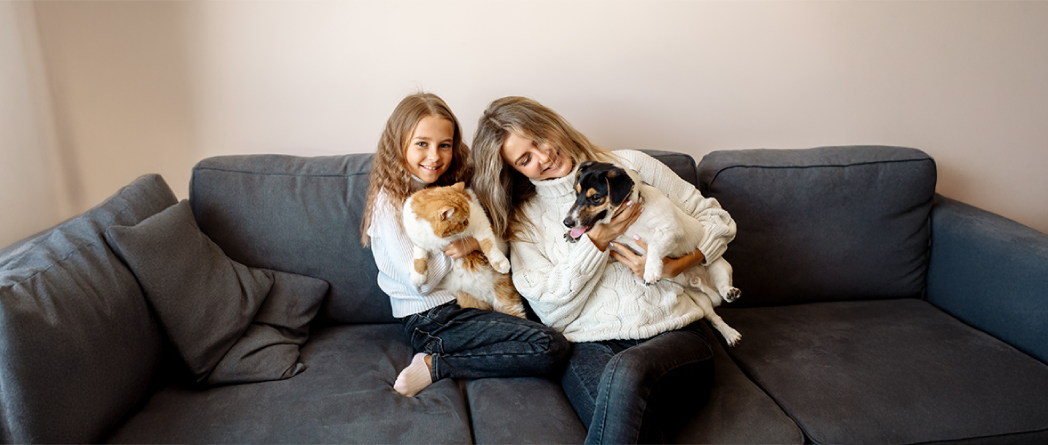 Woman and child cuddling a dog and cat, highlighting pets' role in emotional support